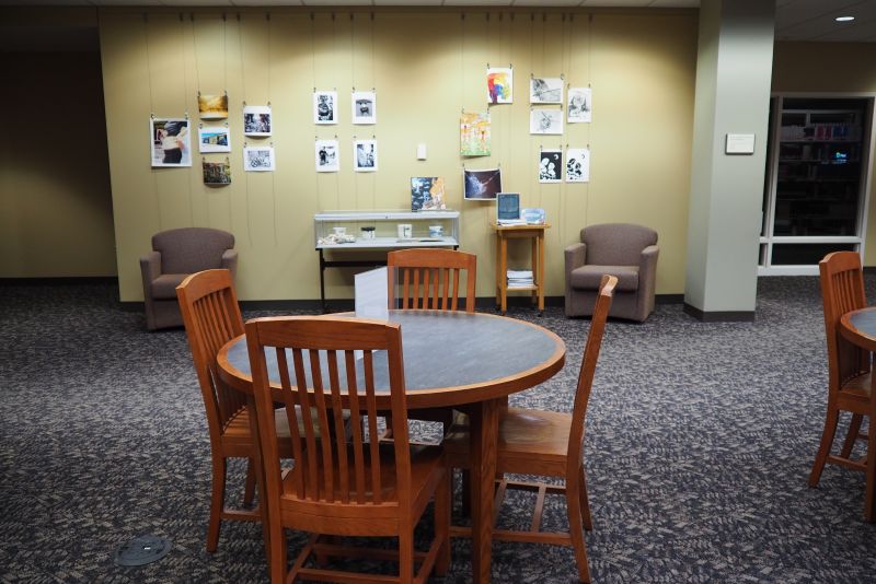 library gallery wall with artwork in front of study tables