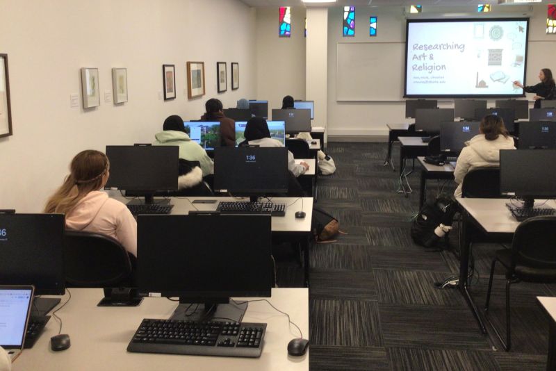 St. Kate's Library classroom with students with computers actively engaged with librarian teaching about researching art and religion
